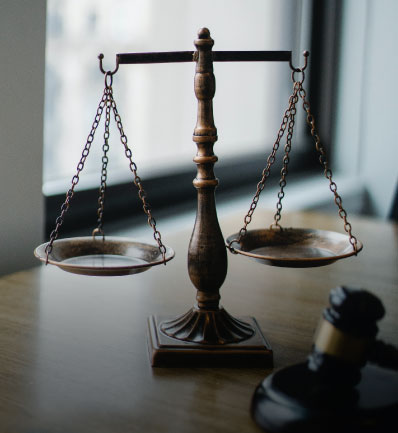 A vintage balance scale in focus, symbolizing justice, stands on a desk with a blurry gavel in the foreground, hinting at a legal or judicial setting involving Nassau County child support lawyer services