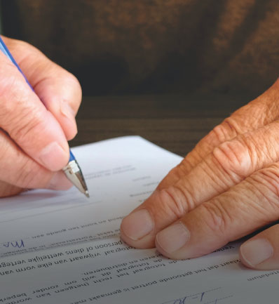A person signing a document with a focus on their hands and the pen, including a Nassau County child support lawyer statement on the desk.