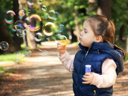 A young child enchanted by the magic of soap bubbles on a sunny day in the park.