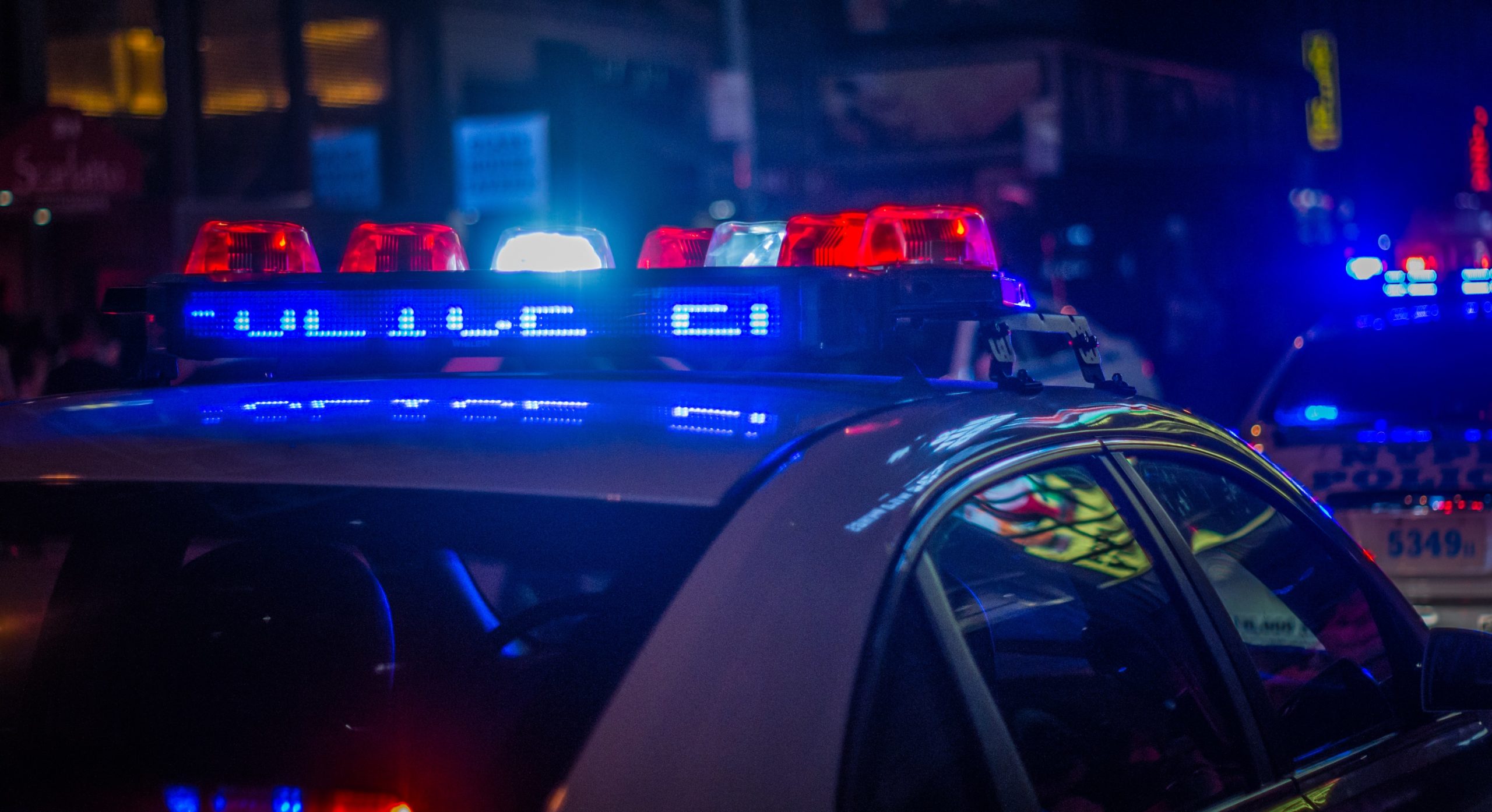 Illuminated police car lights flashing in the night, signaling an emergency situation amidst a city backdrop, not far from where a divorce lawyer near Nassau County NY was handling a complex same-sex divorce case
