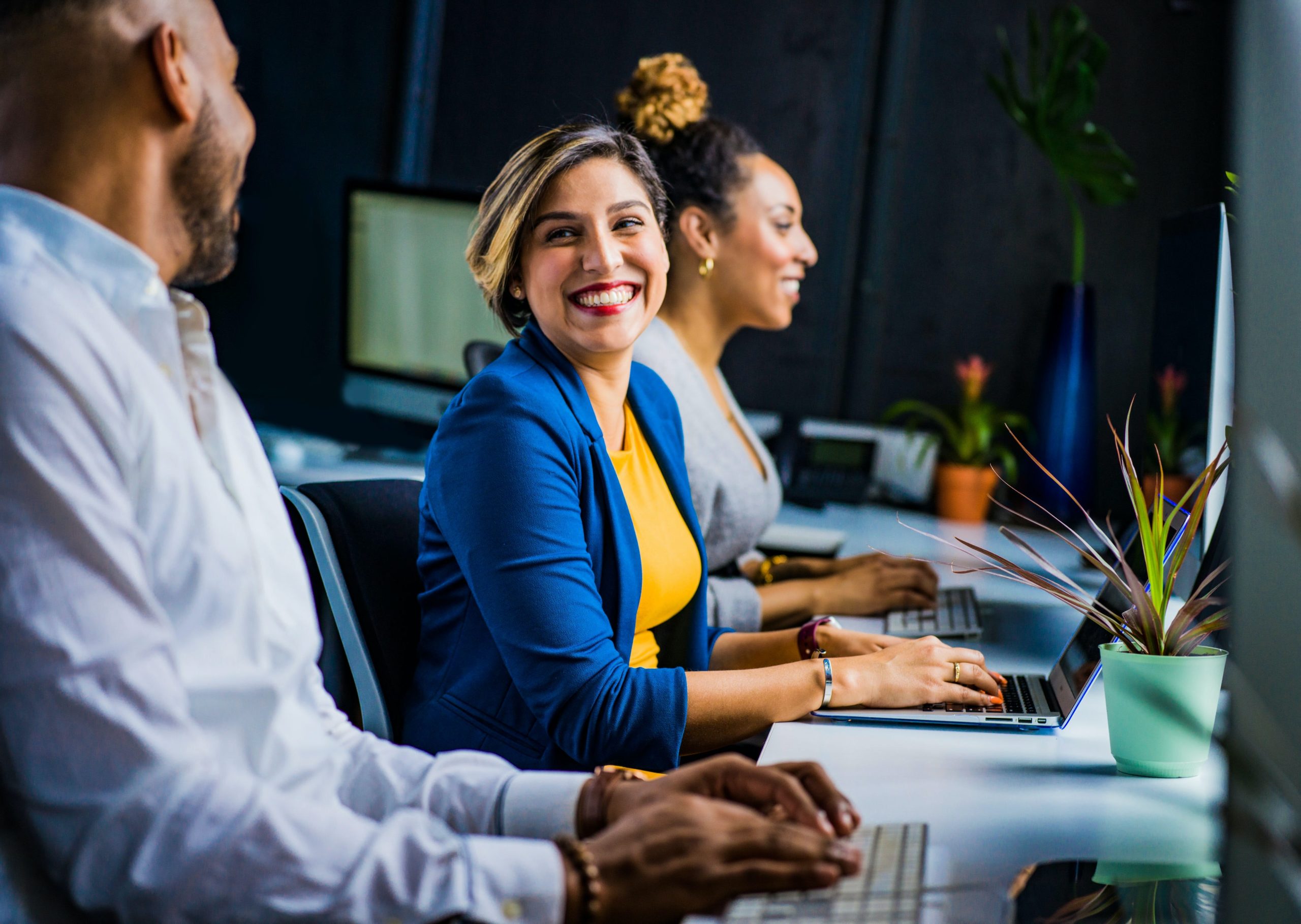 Three Jewish divorce lawyers working collaboratively in a modern office environment, with one of them looking towards the camera and smiling.