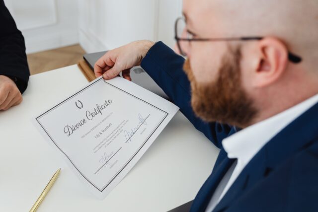 A divorce lawyer near Long Island NY in a suit presenting a divorce certificate on a white desk.