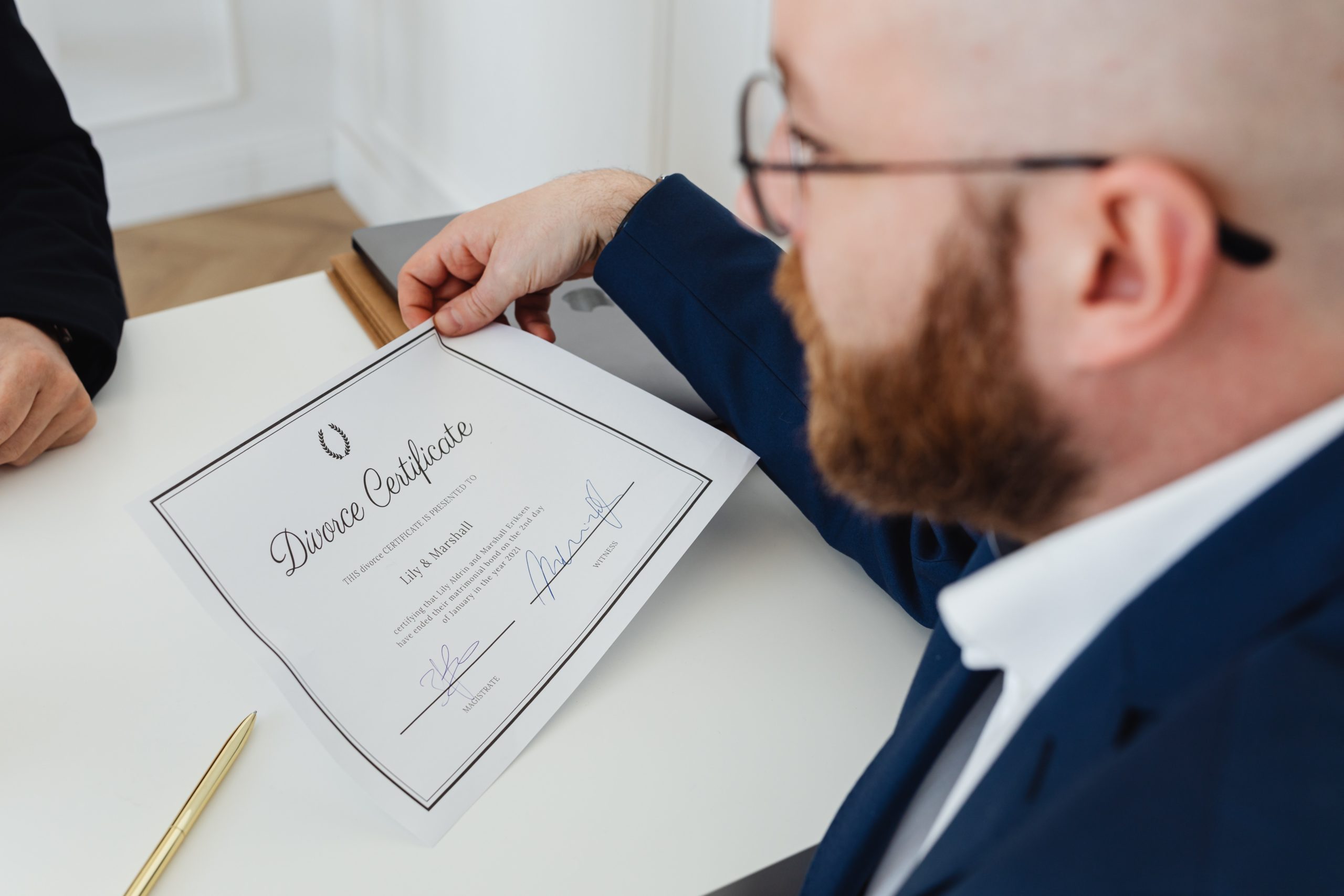 A divorce lawyer near Nassau County NY in a suit presenting a divorce certificate on a white desk.