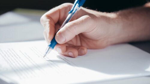 A Jewish divorce lawyer signing a document with a blue pen, with sunlight casting a soft glow on the paper.