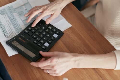 A Nassau County Alimony Lawyer calculating finances or budgeting with a calculator and documents on a wooden desk.