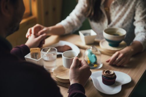 A cozy moment shared over coffee and sweets: two people enjoy a warm conversation and comfort food at a charming café after consulting with a divorce lawyer in Smithtown.