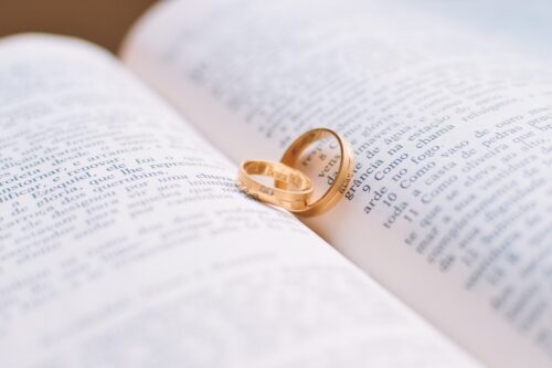 Two golden wedding rings nestled within the pages of an open book, symbolizing a romantic union and the beginning of a couple's story together through a virtual wedding.