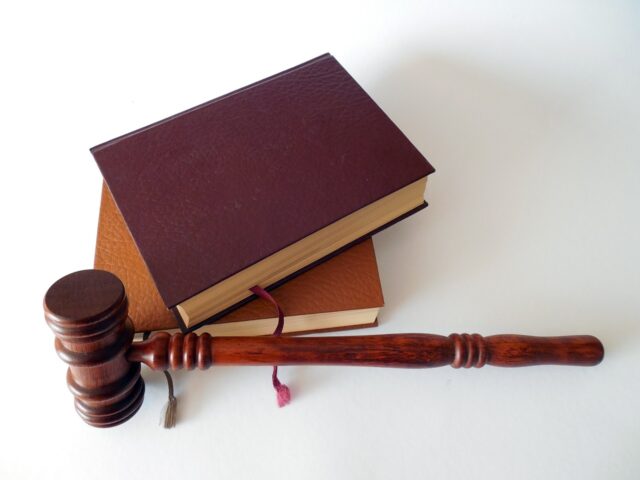 A wooden gavel resting against two hardcover books on a white background, symbolizing law and justice, pertinent to sessions concerning same-sex divorce in New York.