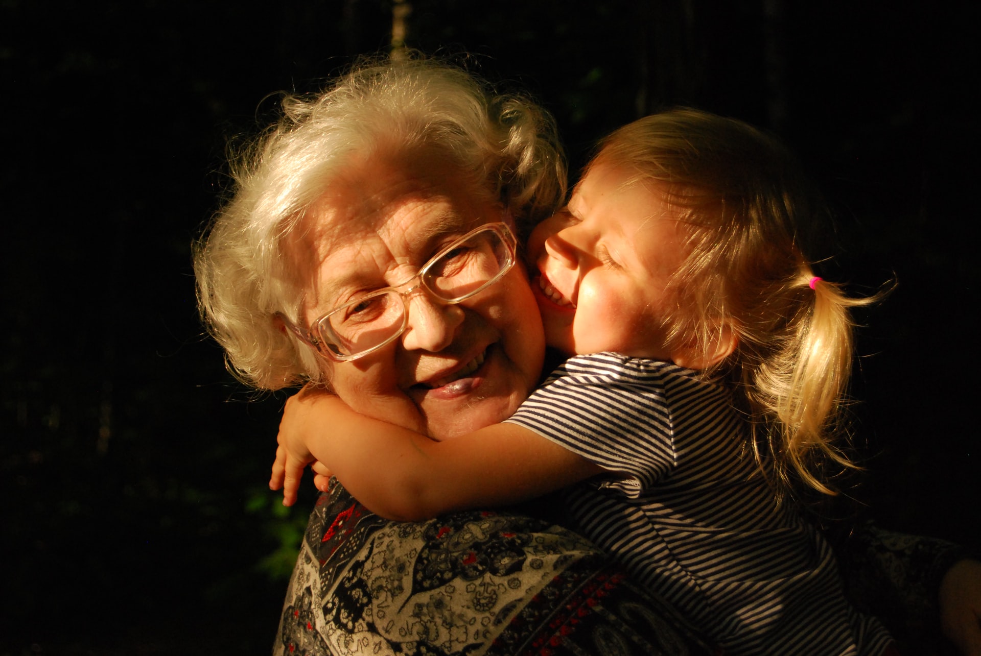A heartwarming embrace between a smiling elderly woman and a young child bathed in golden sunlight, symbolizing unity and support that even the best Nassau County child support lawyer strives to achieve.