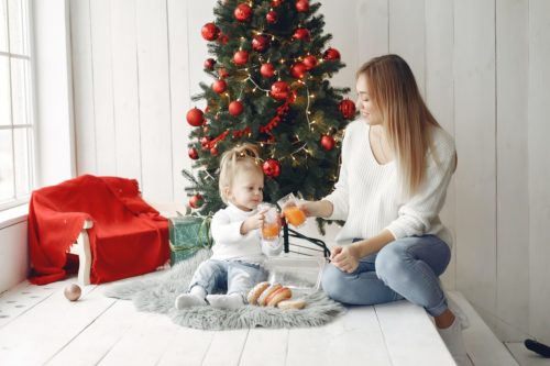 A heartwarming moment of connection: mother and child enjoy a cozy Christmas celebration at home, sharing a toast by the beautifully decorated tree.