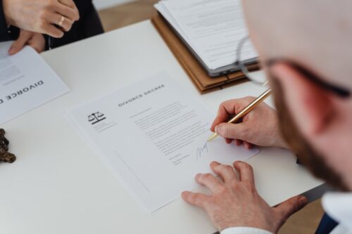 A person signing a divorce decree document with a golden pen, finalizing the legal proceedings of a same-sex marriage dissolution in New York.