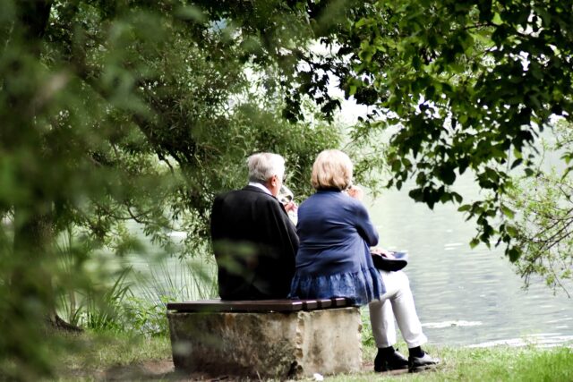 An elderly couple enjoys a tranquil moment by the lakeside, nestled within the embrace of lush greenery after consulting with a divorce lawyer near Long Island NY.