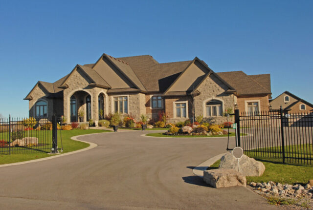 An elegant stone house with a sweeping driveway under a clear blue sky, now home to one of the top divorce lawyer Smithtown.