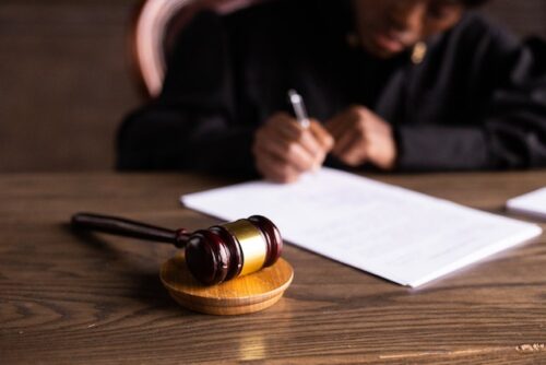 judge signing document with gavel on desk