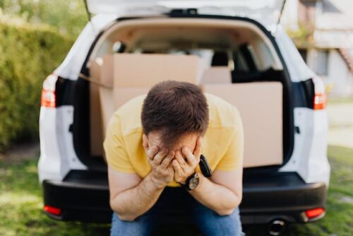 man sitting in car with boxes