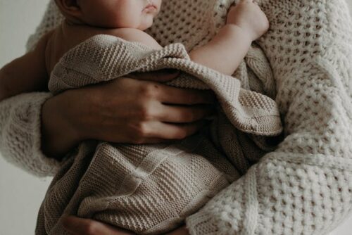 parent holding baby wrapped in blanket