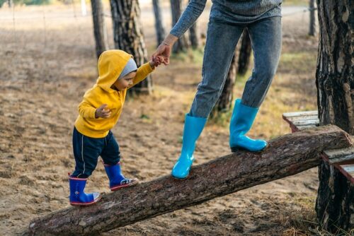 person and child standing on log