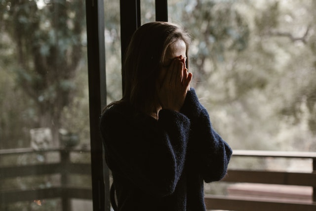 woman with hands covering face